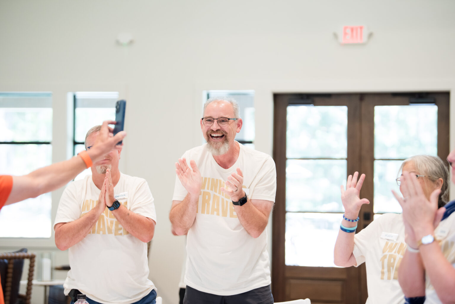 Caregivers applauding in support during a retreat workshop session.