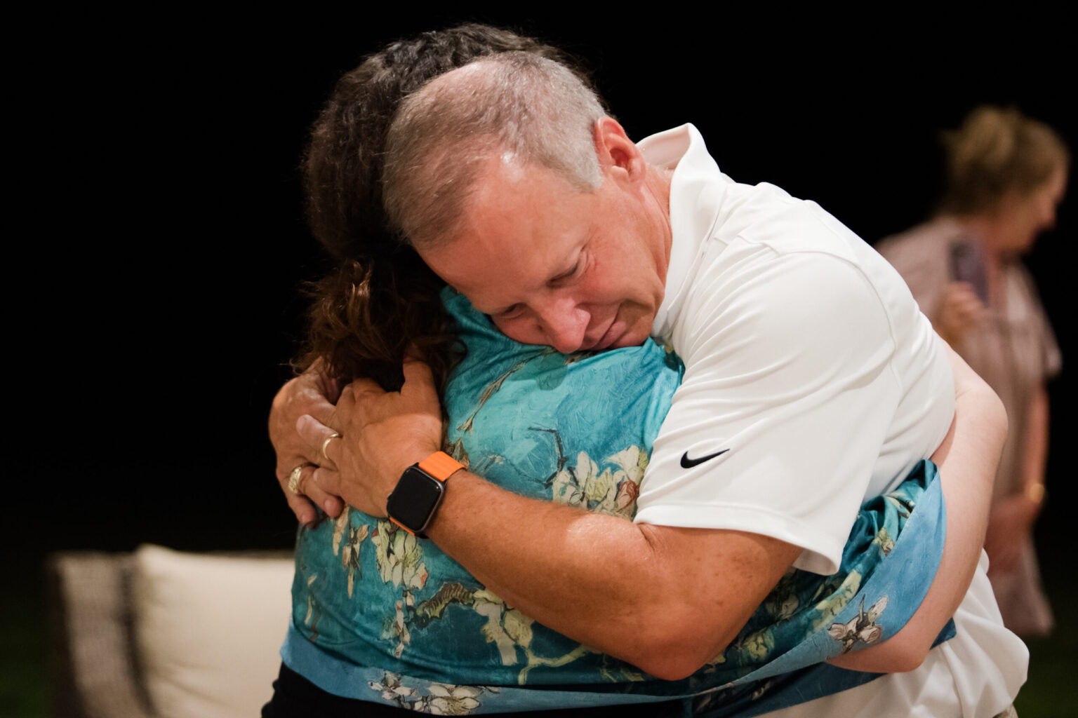 Emotional hug between caregivers during mental health support session.